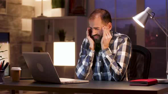 Overworked Businessman Rubbing Temple in Home Office