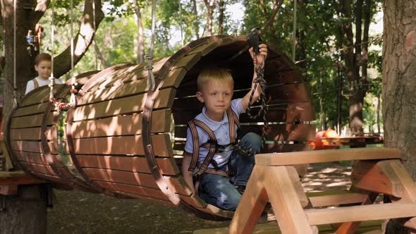 A Little Boy Passes the Obstacles in a Rope Park He Climbs Up a Wooden Tunnel