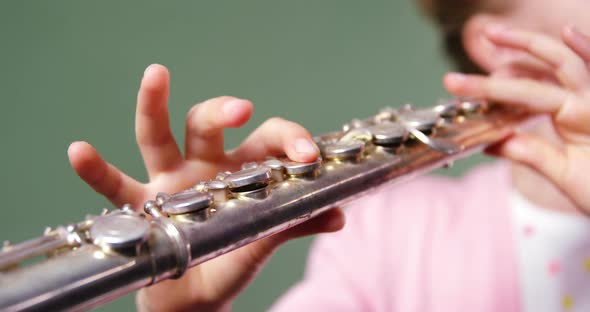 Schoolgirl playing flute in classroom at school