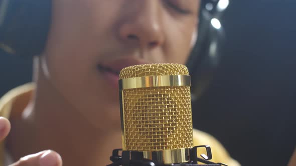 Close Up Of A Condenser Microphone Being Used By A Young Boy Singer On The Black Background