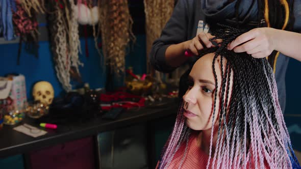 Unrecognizable Person Makes Hairstyle for Young Woman in Salon