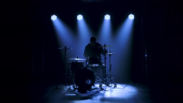 Silhouette Drummer Playing on Drum Kit on Stage in a Dark Studio with Smoke and Neon Lighting