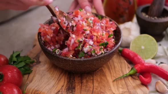 Slow Motion Shot of Woman Mixing Salsa Dip Sauce Ingredients in Wooden Bowl