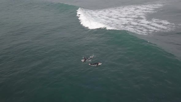 One surfer catches a green wave, another doesn't, retreating aerial