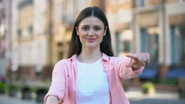 Smiling Woman on Street Making Camera Frame Gesture With Hands