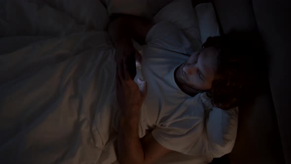 Man Browsing Internet on Phone before Going to Sleep