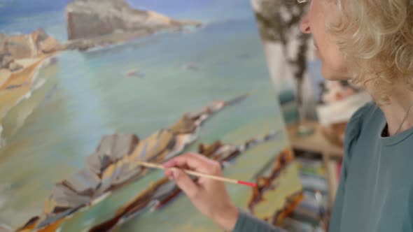 Middleaged White Woman Artist Paints a Picture with Paints