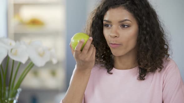 Multiracial Beautiful Woman Eating Apple at Table, Daydreaming, Happy Thoughts