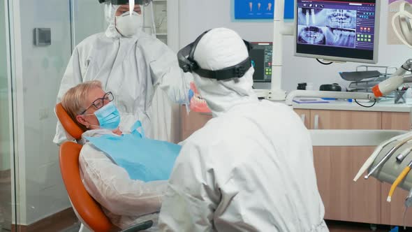 Doctor in Coverall Showing Dental Hygiene Using Mockup of Skeleton