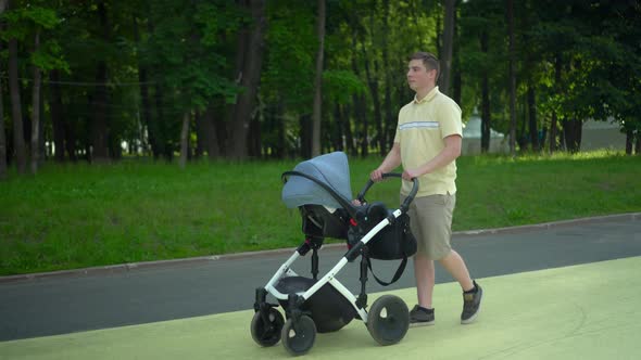 A Young Man Walks with a Baby in a Stroller