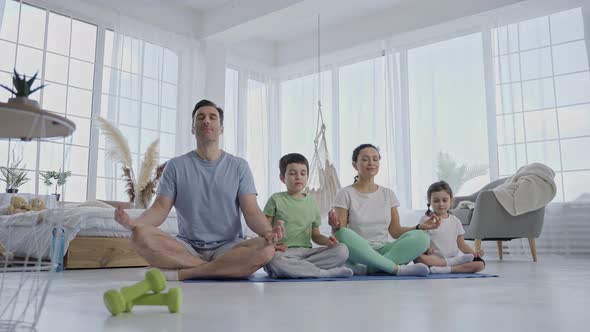 Friendly Family with Kids Practicing Yoga at Home