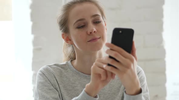 Young Woman Browsing on Smartphone in Loft Workplace