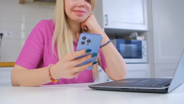 Blonde young woman using mobile phone for internet communication and entertainment