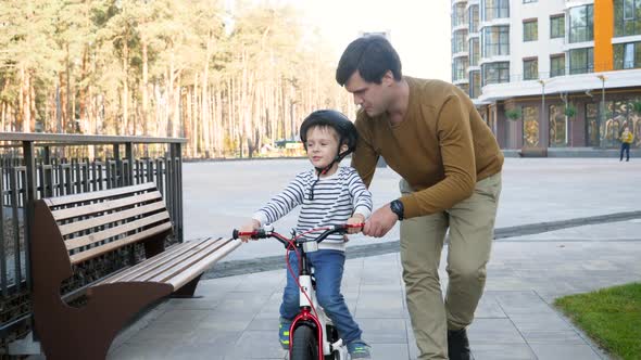  Footage of Happy Young Father Teaching His Little Son Riding Bicycle and Supporting Him