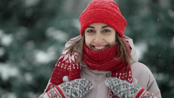 Portrait of Happy Smiling Woman in Knitted Red Hat and Scarf in Snowy Winter Park at Frozzy Day with