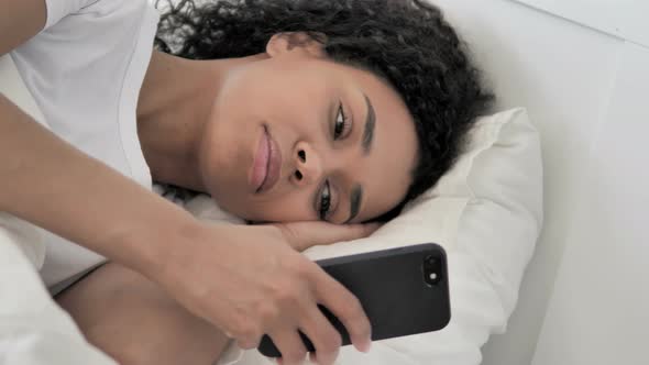 African Woman Using Phone in Bed