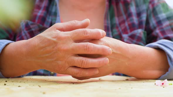 Close Up Front View Hands of an Elderly Woman Lie on a Flat Surface