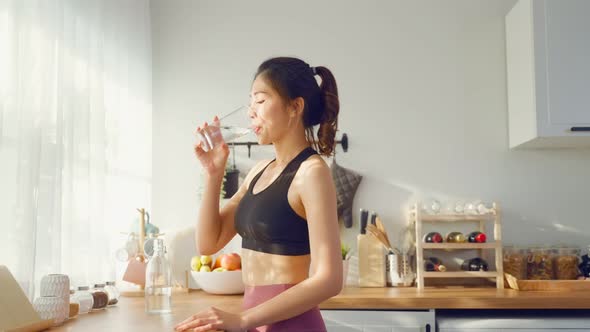 Asian beautiful woman in sportswear drink water after exercise at home.