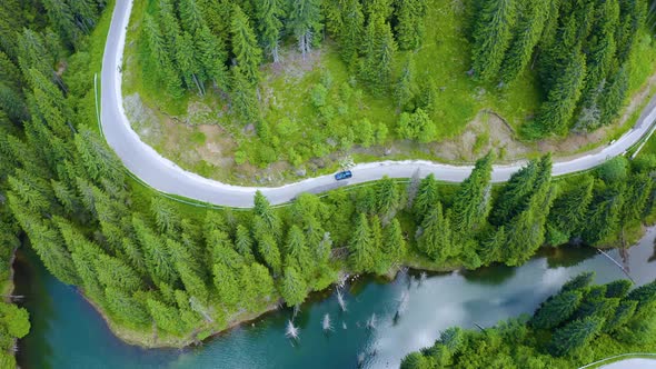 Aerial view of car driving through the fores and the lake on the side. Beautiful mountain road.