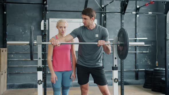 Young Girl Lifting Heavy Barbell Getting Advice From Man Instructor in Gym