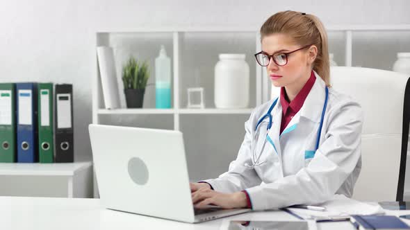 Focused Young Beautiful Female Doctor Working Using Laptop Pc at Modern Clinic