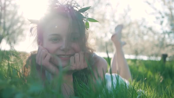 Beauty Smiling Girl lying on the Spring Meadow with wild Flowers. Laughing And Happy. Enjoy Nature.