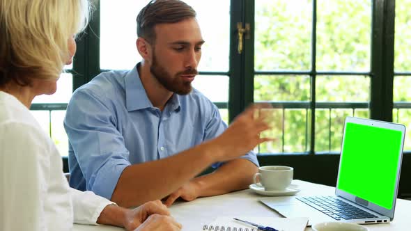 Male and female executives discussing over laptop 4k