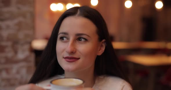 Woman with Enjoyment Drinking Coffee in Cafe