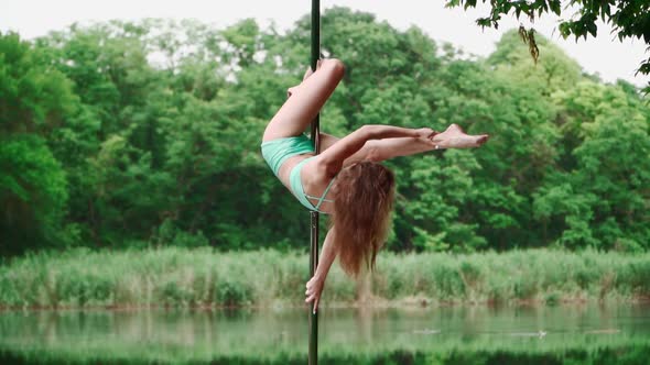 Beautiful Woman with Slim Body Dancing on Background Forest and Lake. Pole Dancer Performs Tricks