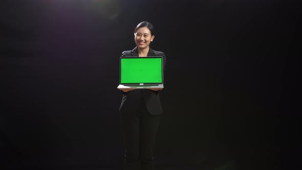 Asian Woman In Business Suit Holding Laptop Computer With Green Screen In The Black Screen Studio