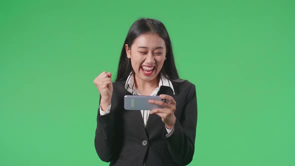 Business Woman Celebrating After Winning Game On Mobile Phone In The Green Screen Studio