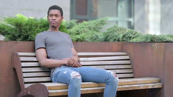 Pensive Young Young African Man Sitting on Bench and Thinking 