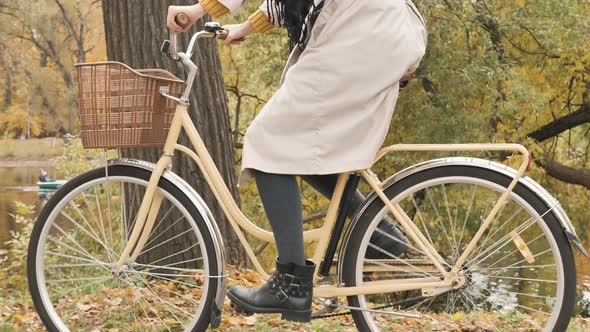 Woman Rides Bicycle Among Trees Past Canal in Autumn Park