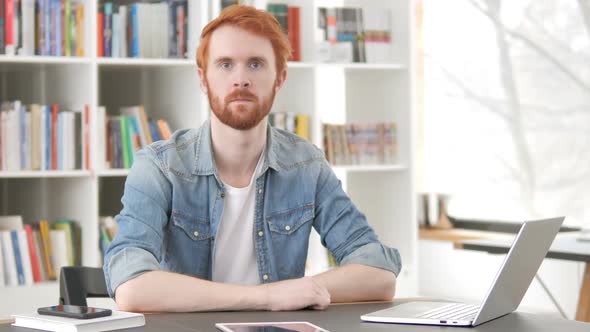 Serious Casual Redhead Man Sitting at Work