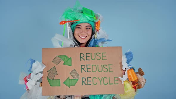 Woman holding cardboard with inscription reuse reduce recycle.