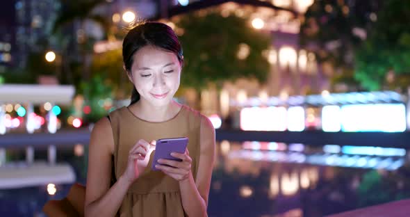 Woman use cellphone in city at night