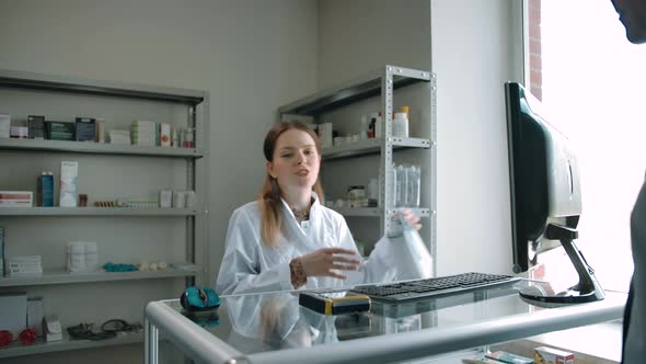 Customer Picks Up Order in White Package From Female Pharmacist at Pharmacy