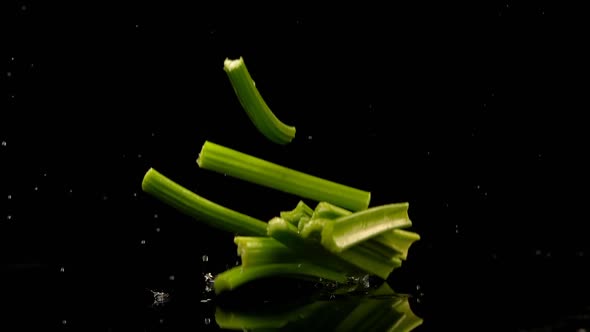 Celery falling on water against black background 4k