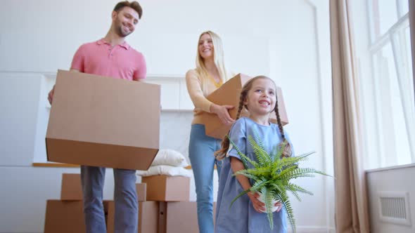 Funny little daughter helps parents with brown cardboard packages