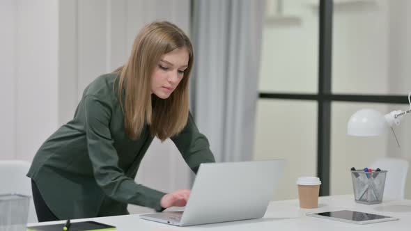 Young Woman Standing While Using Laptop at Work 