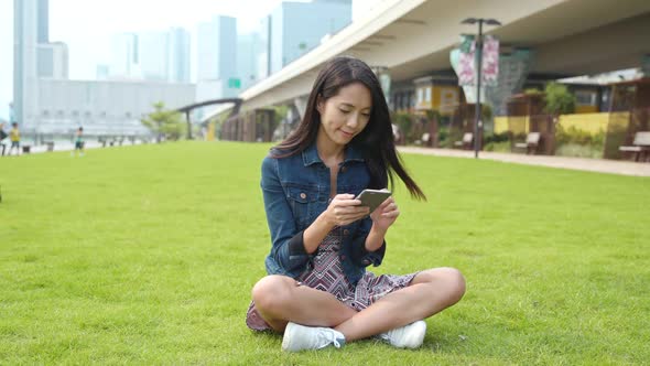 Woman using mobile phone and sitting on the lawn