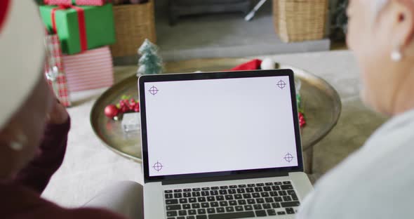 Two happy diverse senior woman on video call on laptop with copy space at christmas time