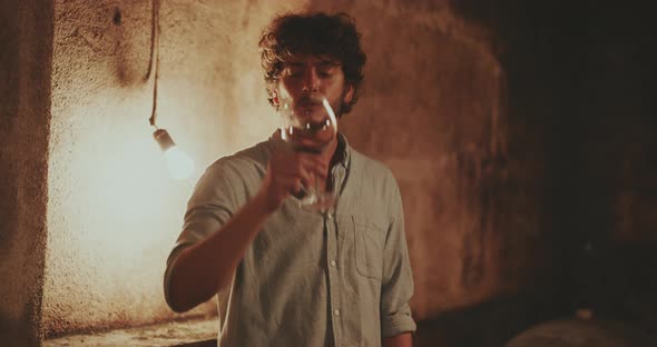 Young man swirling red wine in his glasses then takes a sip