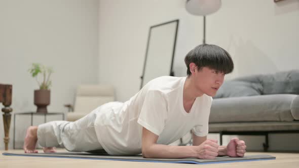 Young Asian Man Doing Plank on Yoga Mat at Home