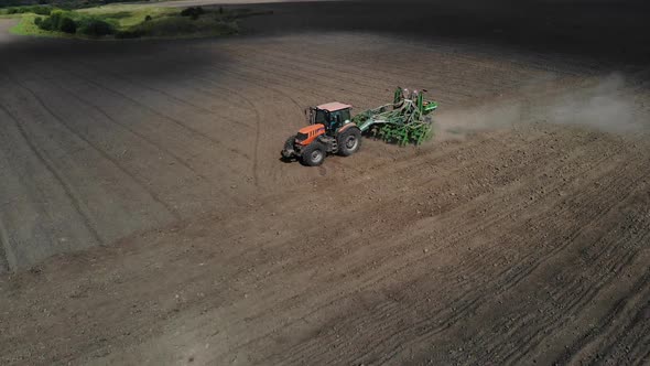 Orange Tractor Plows the Field. Aerial View. 