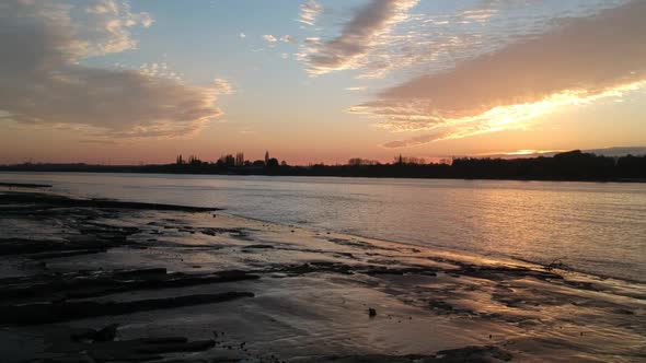 Flying towards silhouette of city on coastline of Schelde river