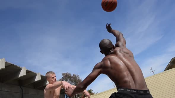 Men playing two-on-two pick up basketball on a playground court.