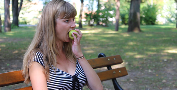 Beautiful Girl Eating Pear in a Park 2