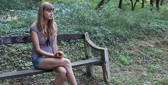 Beautiful Girl Eating Peach in a Park