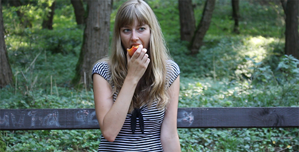 Beautiful Girl Eating Peach in a Park 2